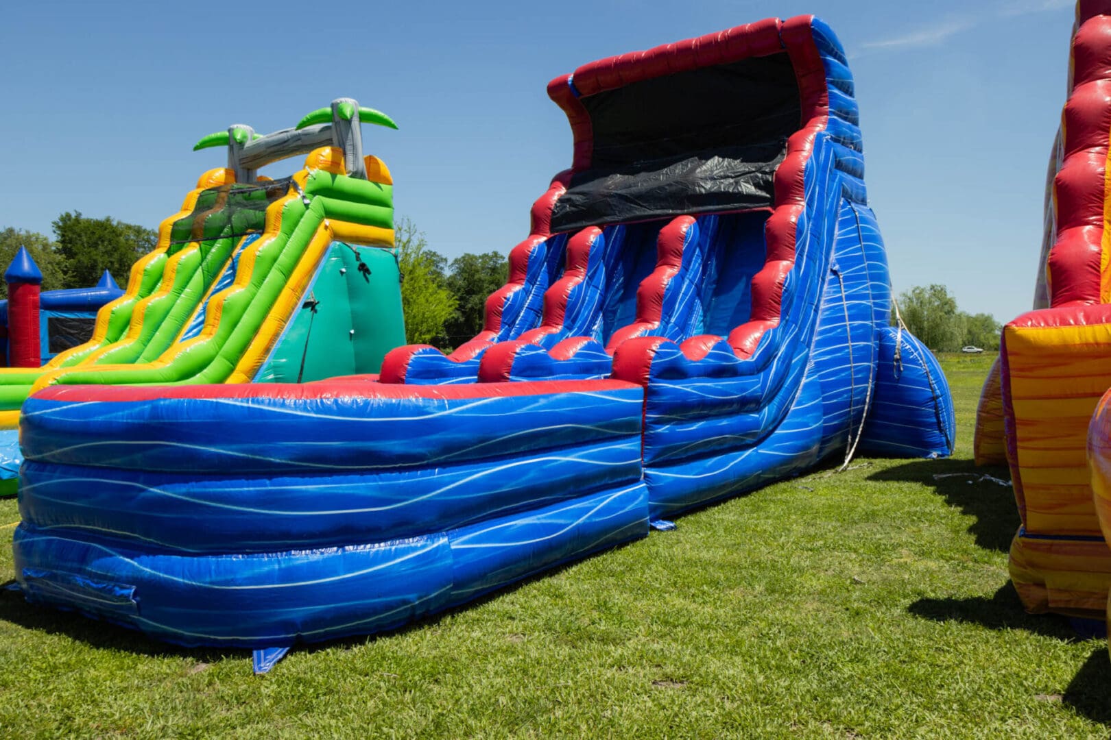 A blue and red inflatable slide on grass.