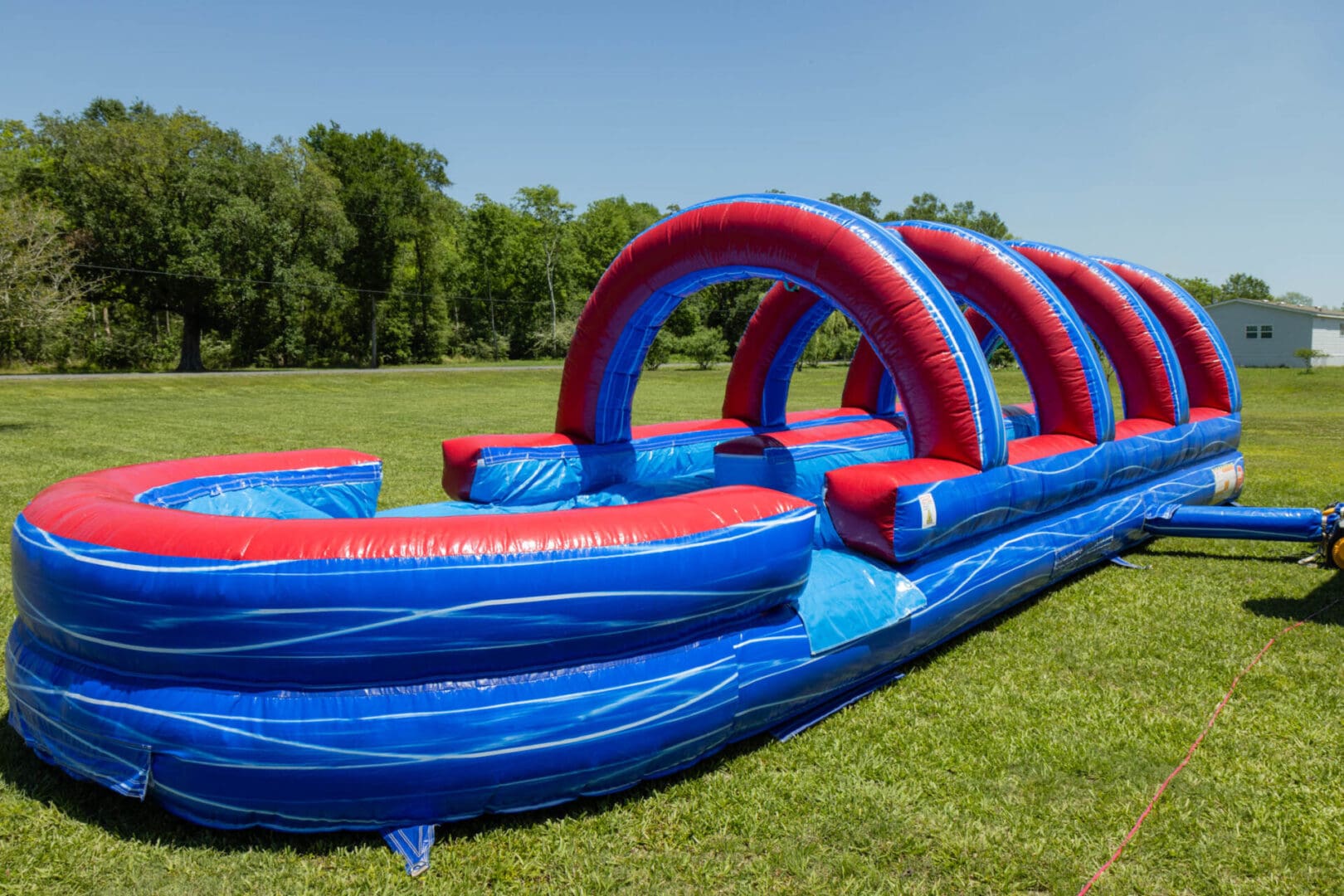 A long inflatable water slide in the grass.